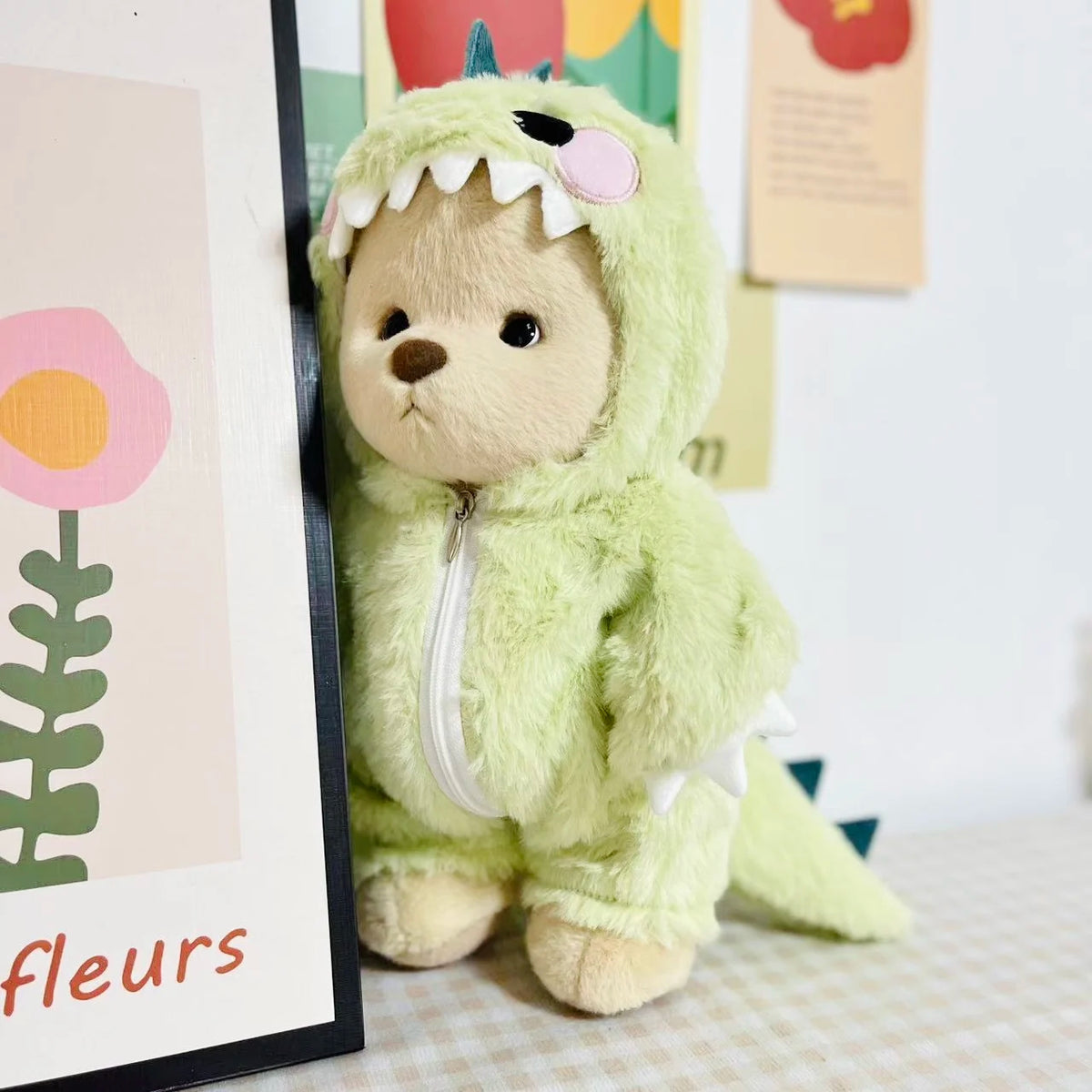 A soft, light green stuffed dinosaur doll wearing a matching jumpsuit outfit.