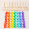 A wooden ring toss game with colored rings in various shades of red, orange, yellow, green, cyan, blue, and purple.