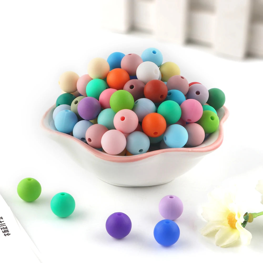 A pile of colorful silicone round beads in various shades of pink, blue, green, and orange for jewelry making
