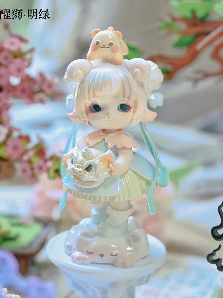 A delicate figurine of a girl with light pink hair and large blue eyes, wearing a light blue dress and holding a small white 