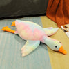 An extra-large plush goose pillow with pink and yellow feathers lying on a light blue surface.