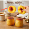 A hand holds a yellow caramel pudding stress ball fidget toy next to a small white cup and a book.