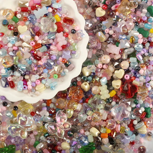 A close-up view of a variety of colorful, translucent glass spacer beads scattered on a white dish.