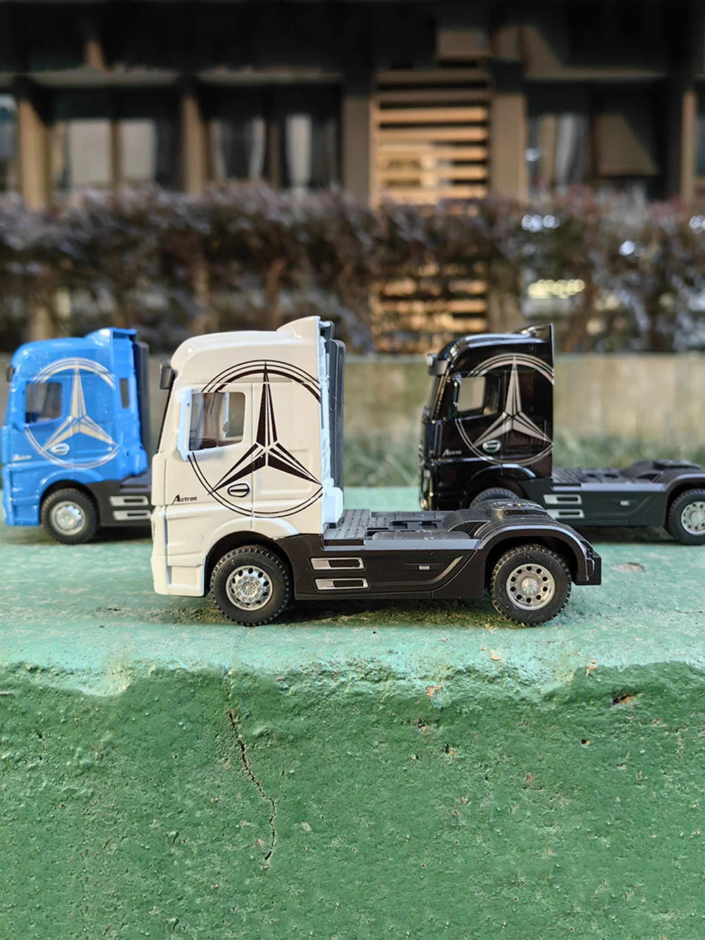 Three diecast alloy container trucks in blue, white, and black are displayed on a green surface.