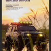 A Toyota Land Cruiser modified for off-road use is shown in a field at sunset, with a spotlight mounted on the roof.
