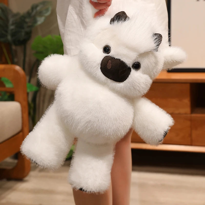 A white plush toy resembling a West Highland Calf or running cow doll is being held by a person.