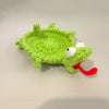 Handmade crochet lizard coaster with green body, white eyes, and red tongue.