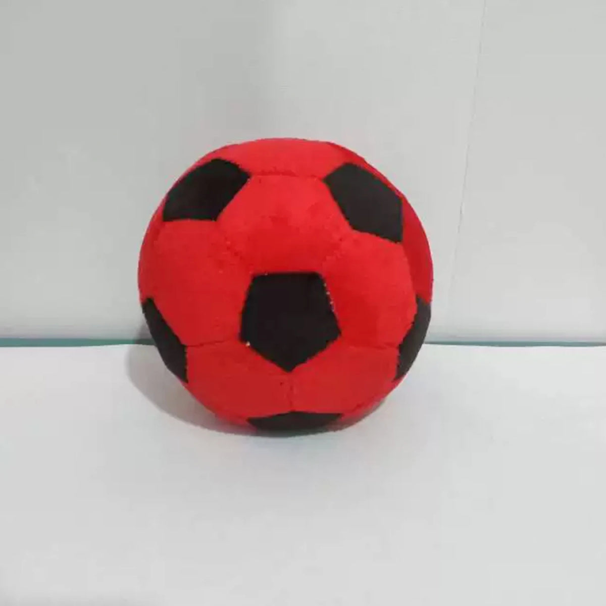A single red and black soccer ball made of crochet is displayed against a white background.