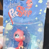 A clear plastic container holding a small pink and orange pet figure from a Little Pet Shop packaging.