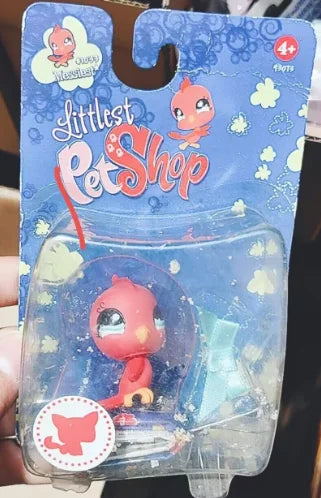 A clear plastic container holding a small pink and orange pet figure from a Little Pet Shop packaging.