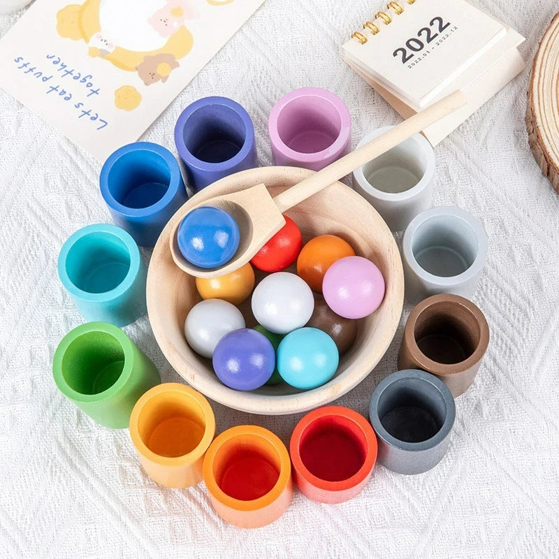 A collection of wooden color sorting game components including rainbow balls and cups in various pastel and vibrant colors.