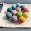 A collection of colorful, smooth, spherical sensory music trees or marbles arranged on a light fabric.
