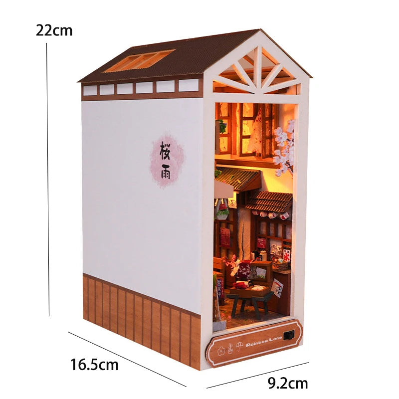 A wooden DIY book nook kit featuring a miniature house with warm LED lighting and detailed interior display.