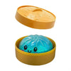 A yellow silicone container holds a translucent blue squishy stress ball shaped like a dumpling.