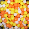 A close-up view of a large pack of colorful play balls in various shades of yellow, orange, and white.