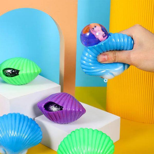 A hand is holding a blue plastic pinch toy shaped like a seashell against a colorful background.