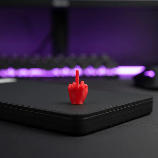 A red, three-fingered hand gesture ornament rests on a black desk surface with purple ambient lighting.