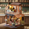 A detailed wooden miniature dollhouse kit of a coffee shop with an awning and display window.