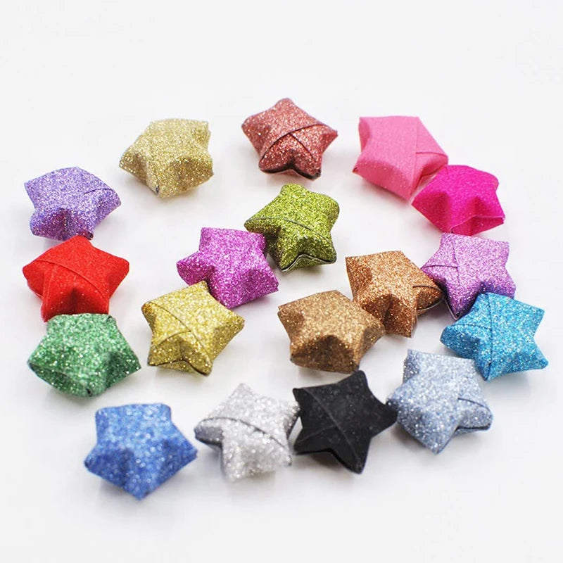 A collection of colorful glitter origami star paper strips arranged in a circular pattern.