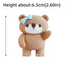 A cute, light brown bear-shaped cake topper with a light blue bow.