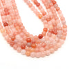 A strand of round rose quartz, amethyst, and red silk jade beads for jewelry making.