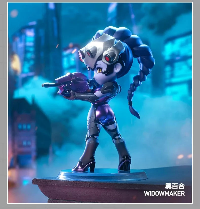 A collectible PVC figurine of Widowmaker in a purple and silver outfit, posed dramatically against a blue cityscape backgroun