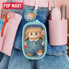 A pink LABUBU doll bag pendant keychain is attached to a denim shirt, next to a pink hairbrush.