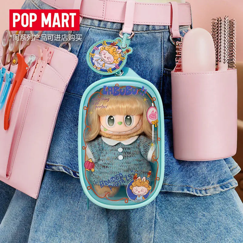 A pink LABUBU doll bag pendant keychain is attached to a denim shirt, next to a pink hairbrush.