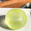 A translucent lime green squishy stress ball resting on a white plate.