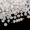 A pile of small, translucent white acrylic bellflower beads for jewelry making.