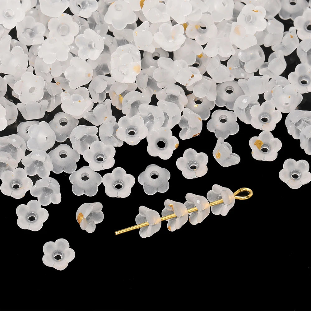 A pile of small, translucent white acrylic bellflower beads for jewelry making.