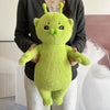 A bright lime green alien cat plush toy is held by a person against a light background.