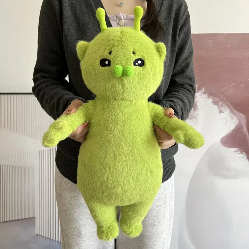 A bright lime green alien cat plush toy is held by a person against a light background.