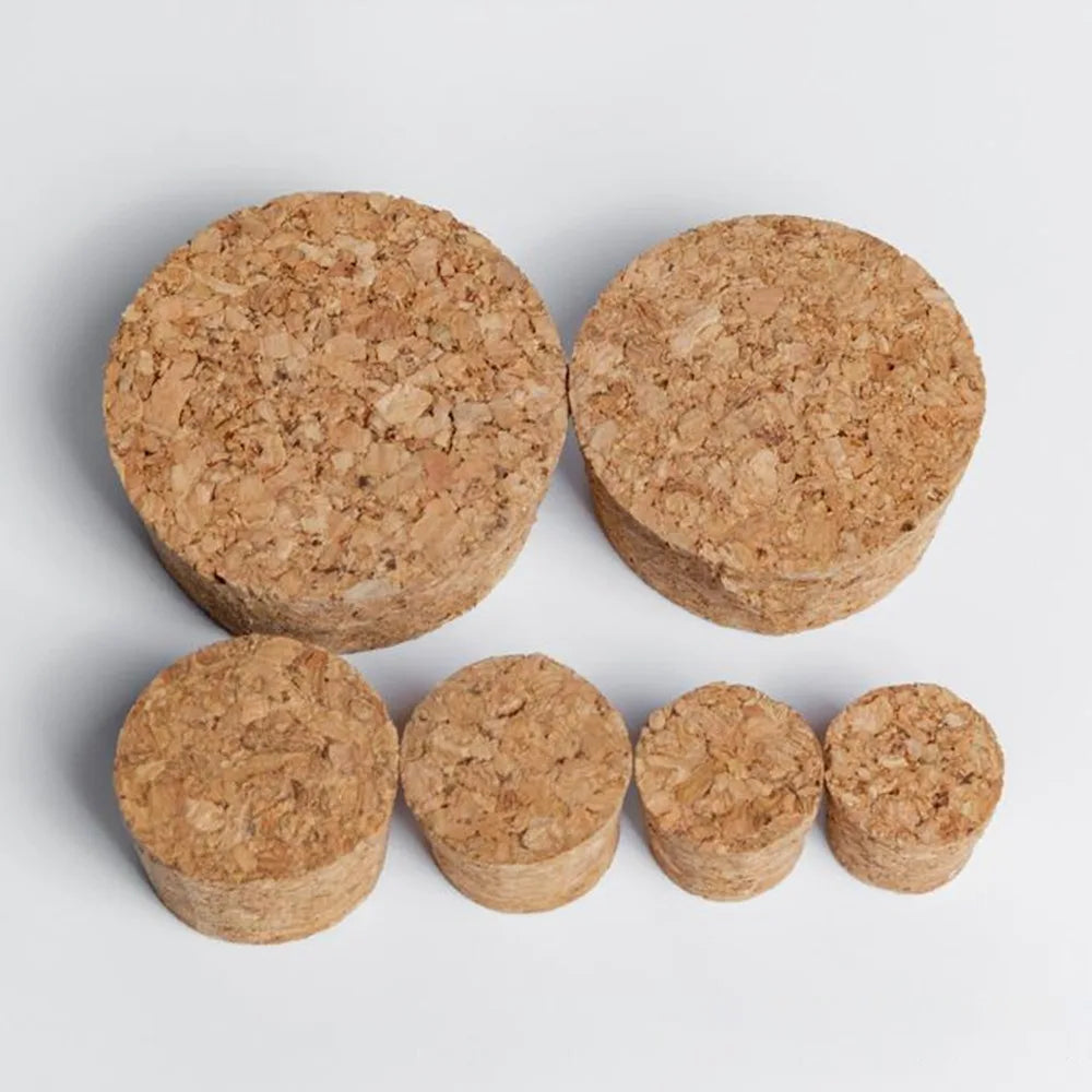 A set of four natural wood tapered bottle and test tube stoppers in various shades of light brown.