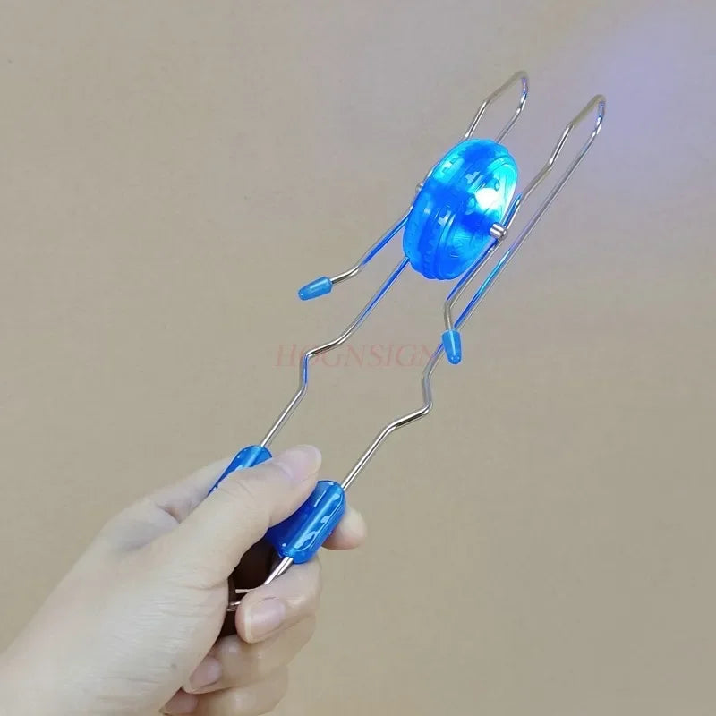 A hand holds a blue retro magic rail twirler toy with a glowing blue orb.