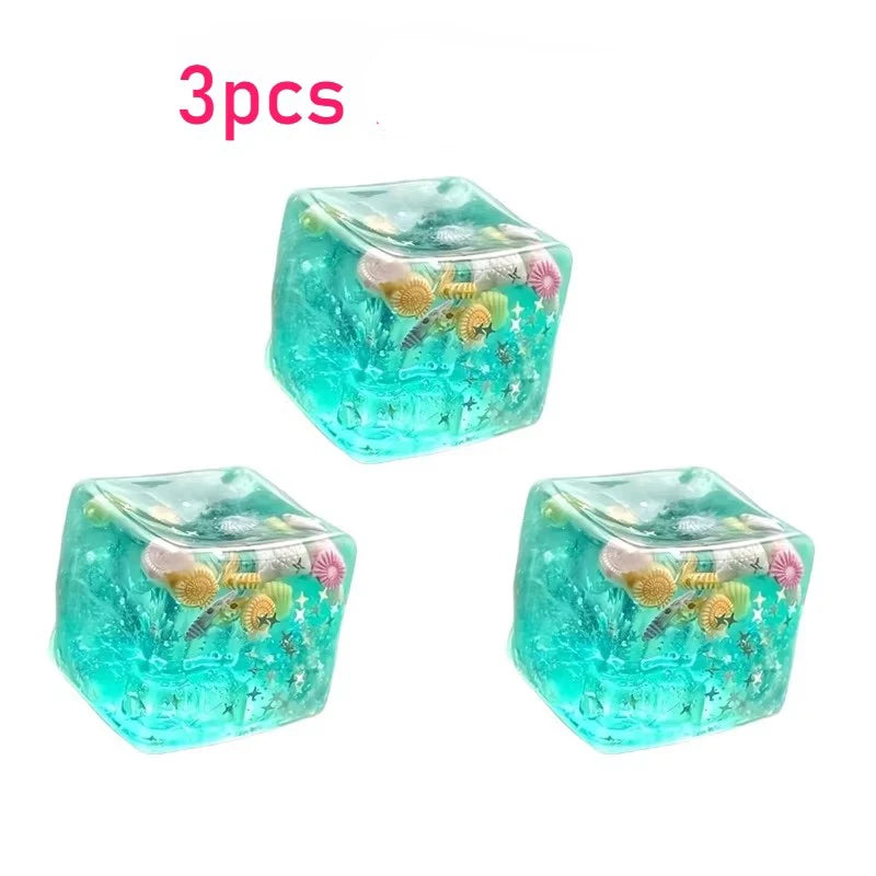 Three translucent teal ocean block squishy stress balls with gold and pink floral accents