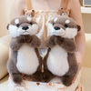 A pair of soft, gray and white magnetic otter plush toys are shown being held in a person's arms.