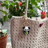 A light beige crochet handbag featuring a hanging keyring with a black and white panda charm.