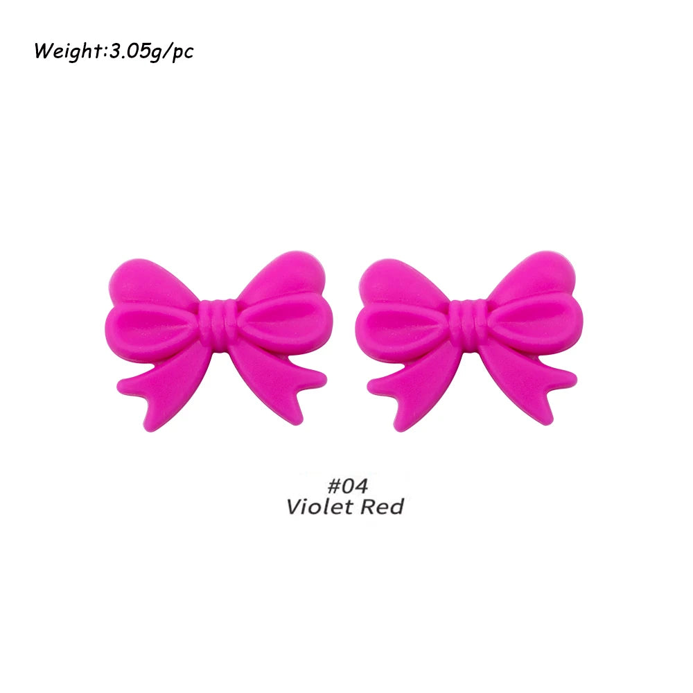 A pair of bright pink silicone bow tie beads used for jewelry making and craft projects.