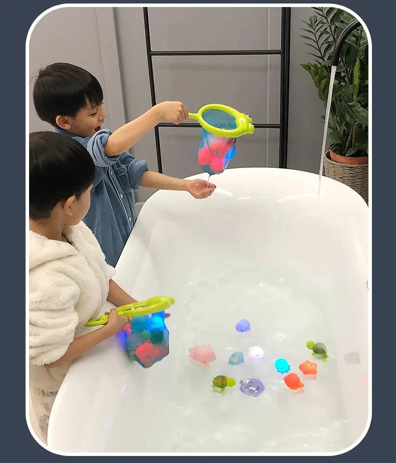 Two children play with glow-in-the-dark animal washing water toys in a white tub.