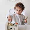 A toddler is using a white Montessori screwdriver board toy for fine motor skills and shape matching.