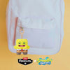 A yellow plush monster keychain with a rabbit design is displayed inside a pink backpack.