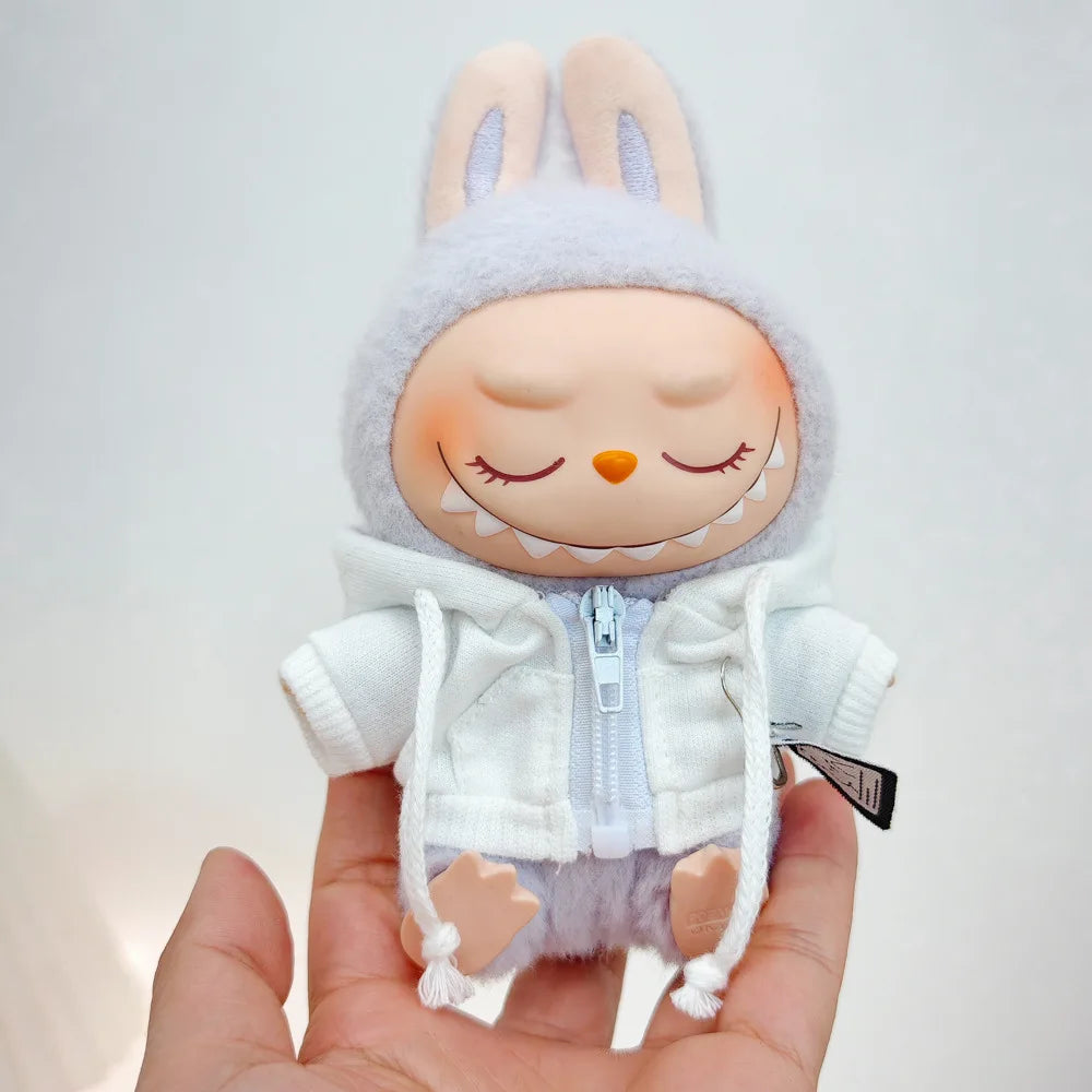 A plush Labubu doll wearing a white hoodie and headphones is held in a hand.