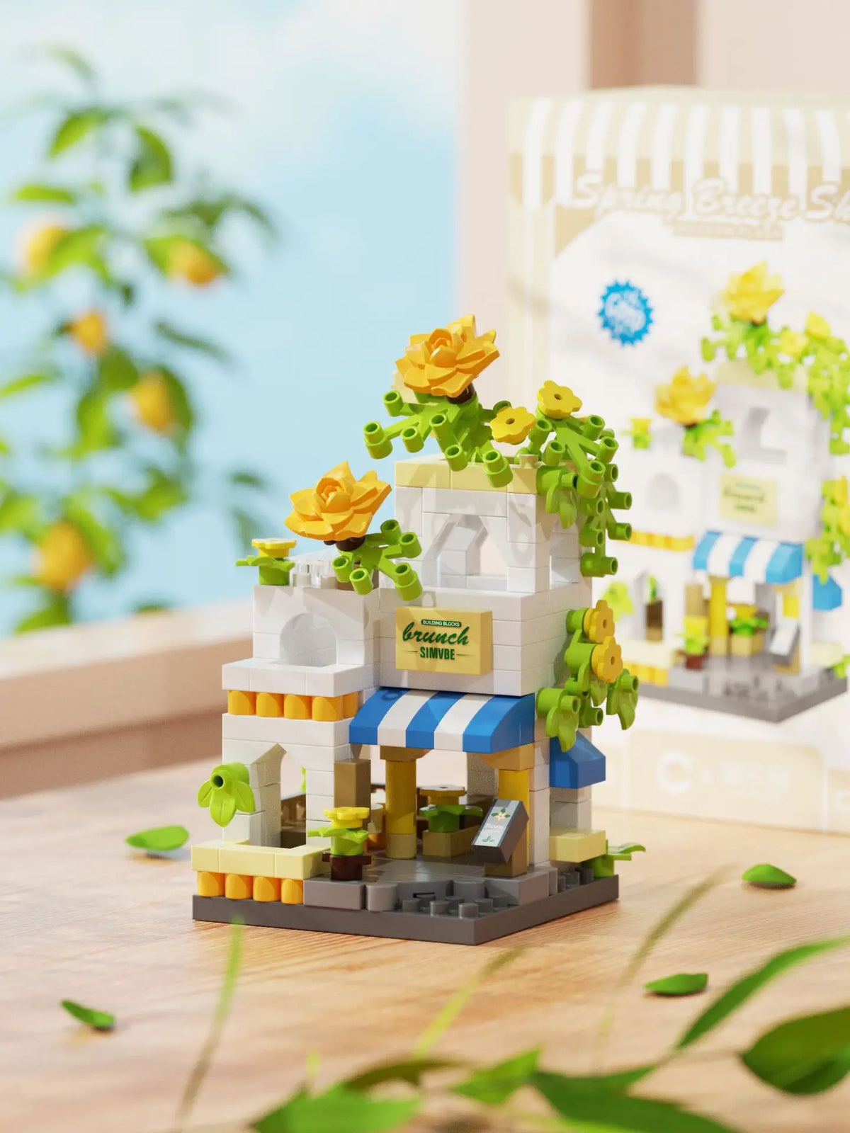 A mini building set featuring a woodland cabin and windmill structure with yellow flowers and green foliage.