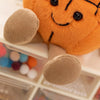 An orange plush sports ball companion with visible feet and a smiling face