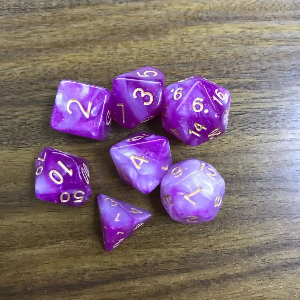 A collection of seven purple acrylic polyhedral dice scattered on a wooden surface.