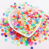 A white bowl filled with colorful polymer clay sprinkles for slime and craft decor scattered around it.