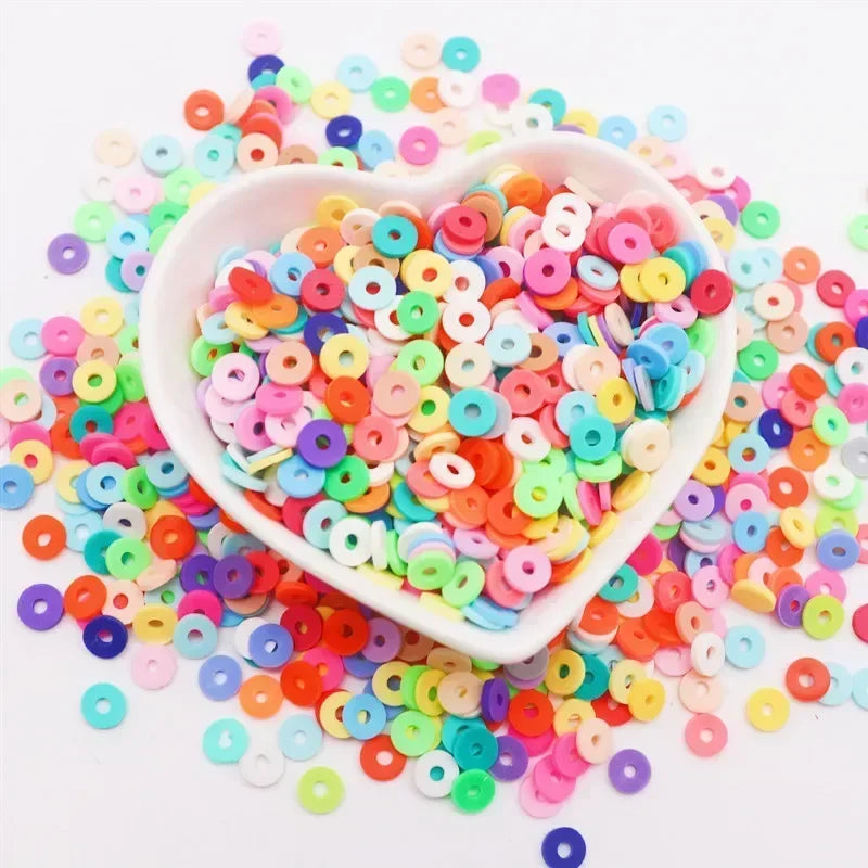 A white bowl filled with colorful polymer clay sprinkles for slime and craft decor scattered around it.