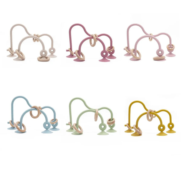 A set of soft silicone teether rings in various pastel colors including pink, purple, beige, and green.