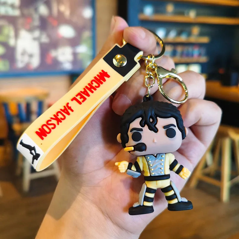 A keychain featuring a small figure of Michael Jackson in a dance pose attached to a wooden tag.